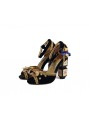 Black velvet sandals with a high block heel, featuring strap closure with a buckle. Gold leather insole