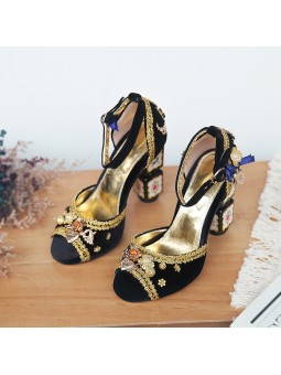 Black velvet sandals with a high block heel, featuring strap closure with a buckle. Gold leather insole